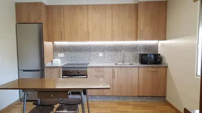 a kitchen with wooden cabinets and a table and a refrigerator at Casa Páez in Pasantes
