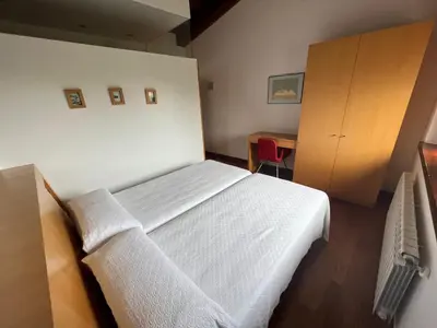 a bedroom with a white bed and a wooden cabinet at Rectoral De Lestedo in Palas de Rei