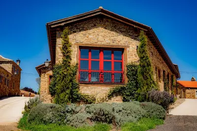 a brick house with a red window on it at Via Avis in Santa Catalina de Somoza