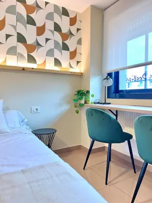 a bedroom with a bed and a desk and chairs at Hostal LA POETISA - Auto Check-in in Culleredo