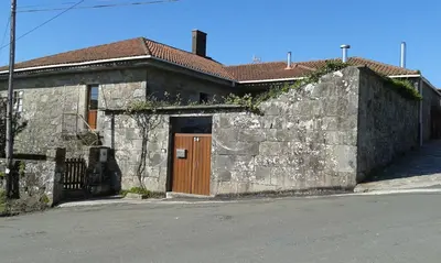 a stone building with a wooden door and a wall at Outeiro de Setecamiños in Cuntis