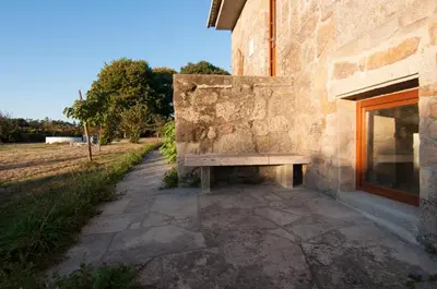 a bench sitting on the side of a stone building at Outeiro de Setecamiños in Cuntis