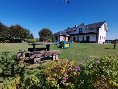 a house with a picnic table in the yard at Apartamentos La Cruz de Paderne in Navia