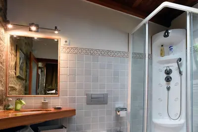 a bathroom with a shower and a sink and a mirror at Casa de Afora Casa con piscina y jacuzzi privados in Santiago de Compostela