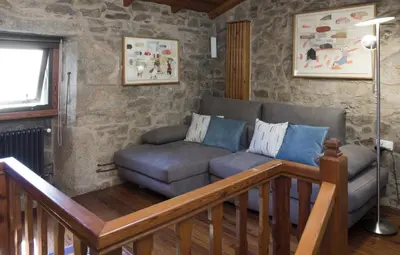 a living room with a couch and a chair at Casa de Afora Casa con piscina y jacuzzi privados in Santiago de Compostela