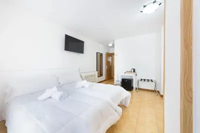 a white bedroom with a white bed and a television at Stellae Luscofusco in Santiago de Compostela