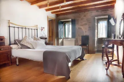 a bedroom with a large bed and a desk at Casa do Cruceiro in As Galanas