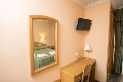 a room with a bed and a mirror and a desk at Hotel PAYRO in Santiago de Compostela