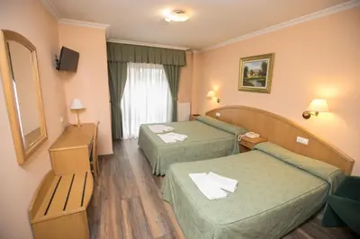 a hotel room with two beds and a mirror at Hotel PAYRO in Santiago de Compostela