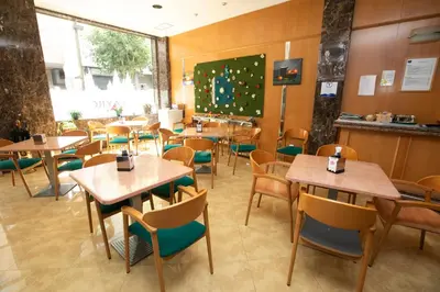 a restaurant with tables and chairs and a large screen at Hotel PAYRO in Santiago de Compostela