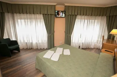 a bedroom with a green bed with white towels on it at Hotel PAYRO in Santiago de Compostela