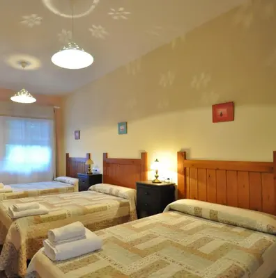 a bedroom with three beds and a window at Hotel Rural Aguallevada in Paramio