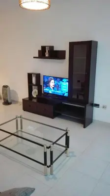 a living room with a tv and a glass table at Apartamentos Loyo in Portomarin