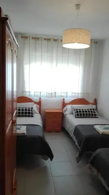 a bedroom with two beds and a large window at Apartamentos Loyo in Portomarin