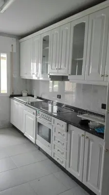 a kitchen with white cabinets and black counter tops at Apartamentos Loyo in Portomarin