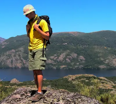 a man with a backpack standing on top of a rock at Hospedería El Pico del Fraile in Cobreros