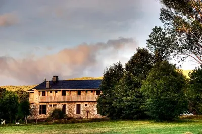 an old stone house in a field with trees at Hospedería El Pico del Fraile in Cobreros