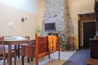 a living room with a tv on a stone wall at Hospedería El Pico del Fraile in Cobreros