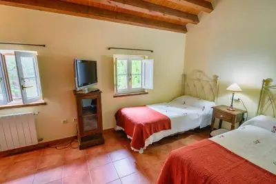a bedroom with two beds and a flat screen tv at Hotel Rural La Casa del Burrero in Castropol