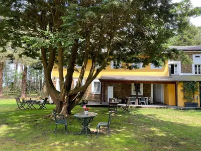 a table and chairs under a tree in front of a house at Hotel Rural La Casa del Burrero in Castropol