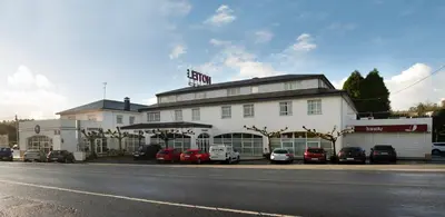 a large white building with cars parked in front of it at Hotel Barreiro in Leira