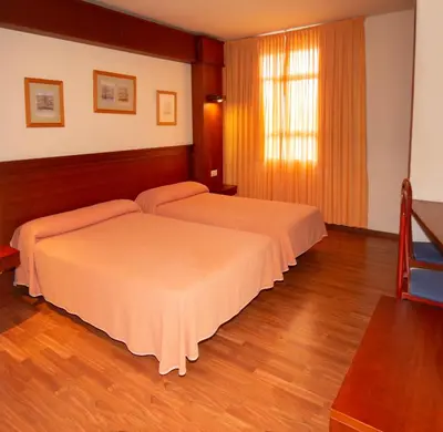 two beds in a hotel room with wood floors at Hotel Barreiro in Leira