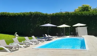 a pool with chairs and umbrellas next to a hedge at Hotel Barreiro in Leira