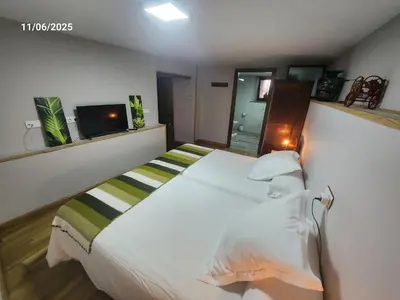 a bedroom with a white bed and a television at VV La Pumarada De Limés II in Cangas del Narcea