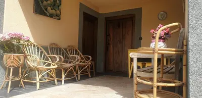 a porch with chairs and a table and a door at VV La Pumarada De Limés II in Cangas del Narcea