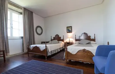 a bedroom with two beds and a blue chair at Pazo de Sedor in Arzúa