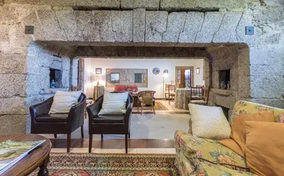 a living room with couches and a stone wall at Pazo de Sedor in Arzúa