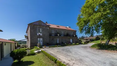 a large stone building with a road in front of it at Pazo de Sedor in Arzúa