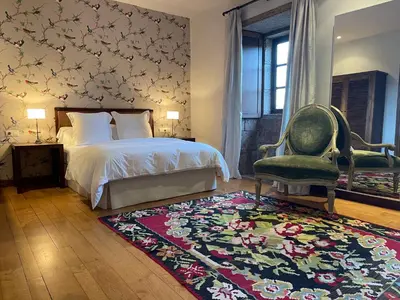 a bedroom with a bed and a chair and a rug at Rectoral de Cines in Oza dos Ríos