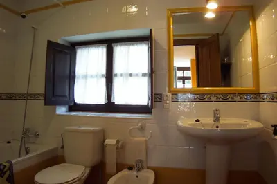a bathroom with a toilet and a sink and a mirror at La Corona del Auteiro in Valle de Lago