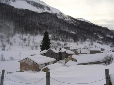a village covered in snow in front of a mountain at La Corona del Auteiro in Valle de Lago
