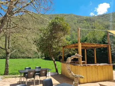 a wooden gazebo with a table and chairs at cabañas bungalow albergue camping valle do seo in Trabadelo