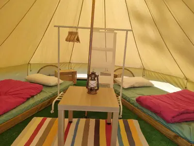 a room with two beds and a table in a tent at cabañas bungalow albergue camping valle do seo in Trabadelo