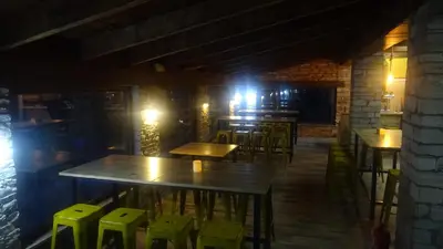 a bar with wooden tables and green stools at cabañas bungalow albergue camping valle do seo in Trabadelo