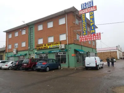 a building with cars parked in a parking lot at Hostal Residencia Delfin in Astorga