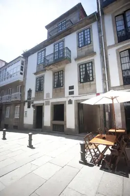a table with an umbrella in front of a building at Carris Casa de la Troya in Santiago de Compostela