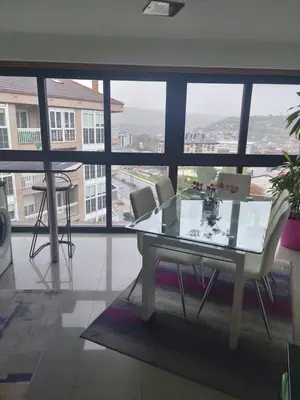 a table and chairs in a room with a large window at Duplex grandes cristaleras impresionantes vistas in Ourense