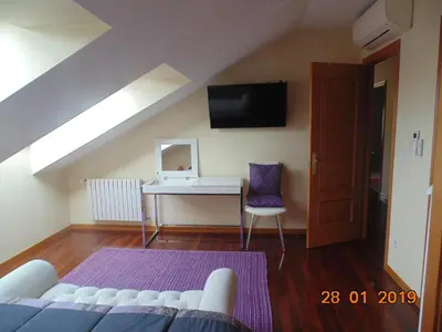 a attic room with a couch and a desk and a tv at Duplex grandes cristaleras impresionantes vistas in Ourense