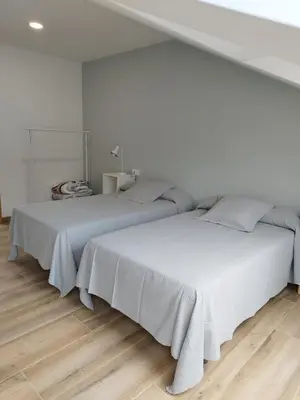two beds in a white room with wooden floors at Pensión Residencial Platas in O Pedrouzo