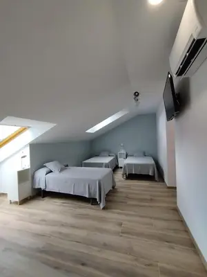 a bedroom with two beds and a flat screen tv at Pensión Residencial Platas in O Pedrouzo