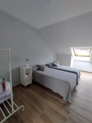a white bedroom with two beds and a window at Pensión Residencial Platas in O Pedrouzo