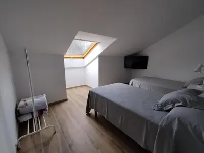 a attic bedroom with two beds and a window at Pensión Residencial Platas in O Pedrouzo