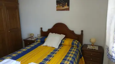 a bedroom with a bed with a yellow and blue blanket at PRECIOSA CASA DE 4 HABITACIONES EN PLENO CORAZÓN DEL CAMINO DE SANTIAGO! in Palas de Rei
