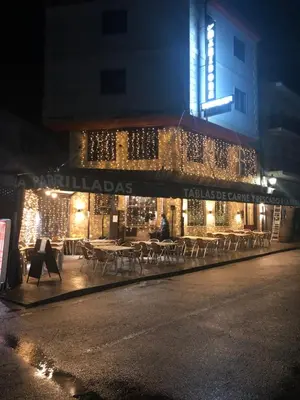 a building with tables and chairs on a street at night at Hotel tres estrellas Casa Maribona Gela in El Puente