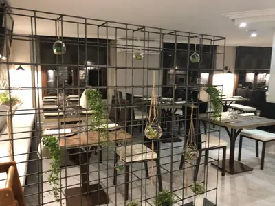a restaurant with tables and chairs and potted plants at Hotel tres estrellas Casa Maribona Gela in El Puente