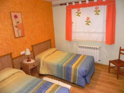 two beds in a room with orange walls and a window at O Lar de Carmiña in Devesa